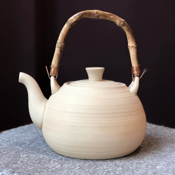 braune Teekanne aus Keramik mit Bambusgriff
